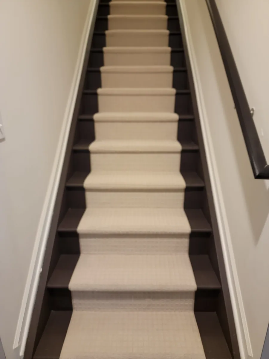 Narrow staircase with new beige carpet and white walls