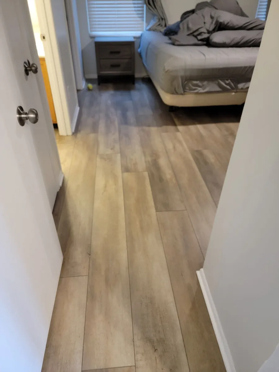 Wood-look luxury vinyl plank flooring in a hallway leading to a bedroom