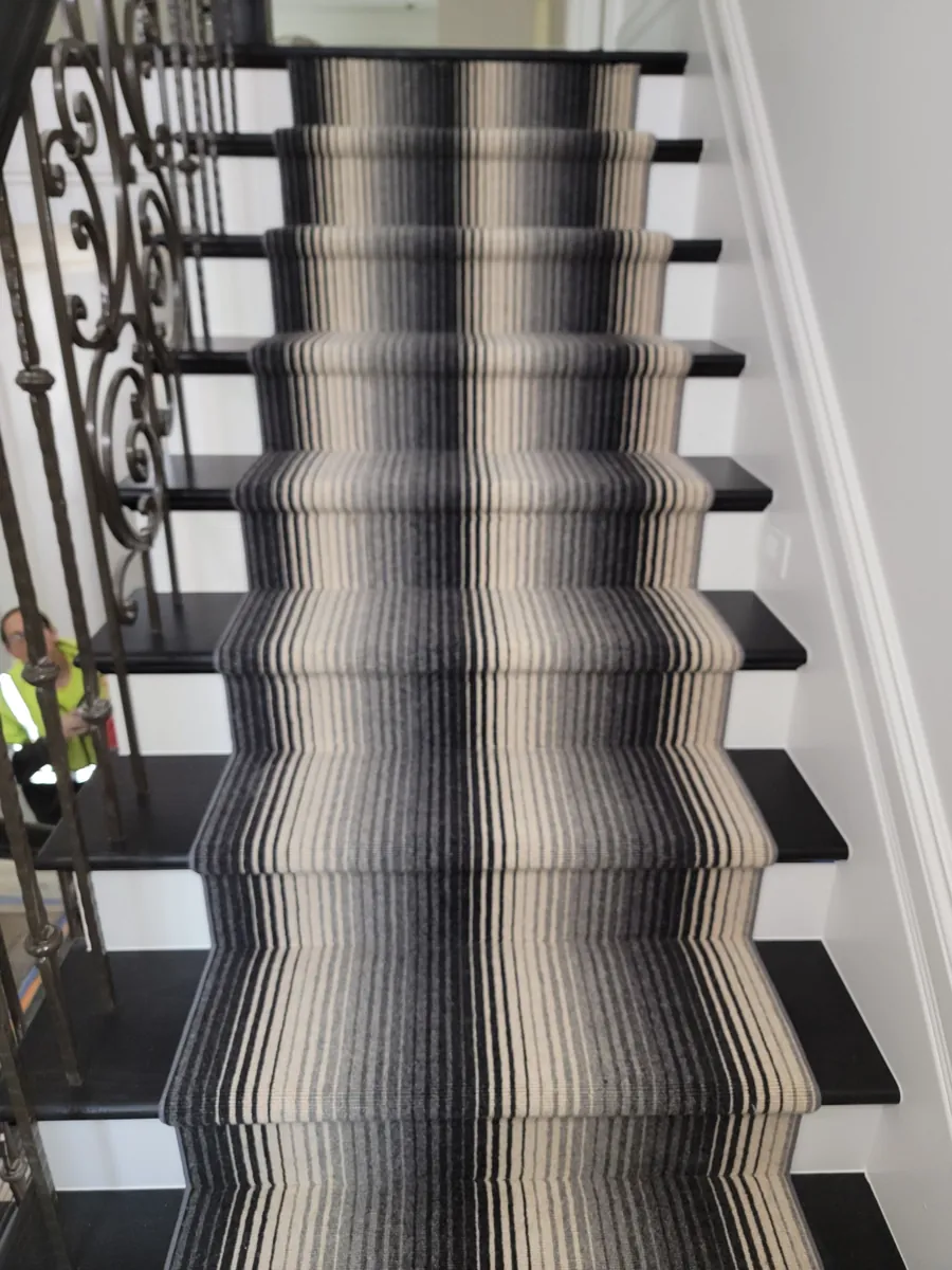 Black-and-white striped stair runner with decorative iron railing